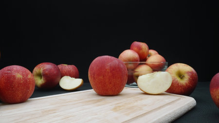 Macrography of apples displayed in various forms: whole, sliced, and within a glass bowl with black...