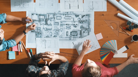 Group of people looking at blueprint while brainstorming idea. Top view of engineer team looking and...