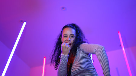 Low angle camera of hispanic dancer looking at camera and dancing to city pop music. Professional...