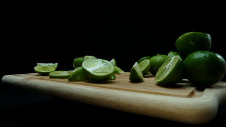 Close-up, a vibrant slice of fresh lime rests upon a rustic wooden cutting board, exuding freshness and vitality. The translucent membranes of the green lime slice placed on cutting board. Comestible.の写真素材