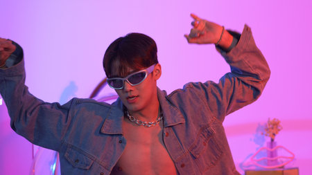 Close up of asian street dancer moving to pop music with neon light while diverse friend sitting and...