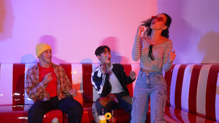 Diverse street dancer moving to city pop music at party with neon light while wearing hippie...