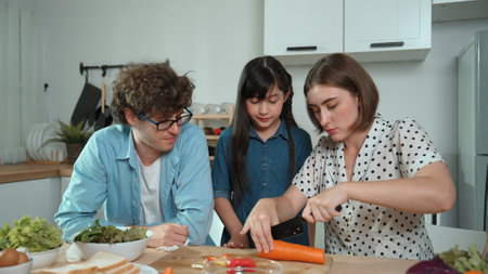 Happy father move to music while cooking food and prepare lunch at modern kitchen. Active dad dancing to song while making healthy food or salad surrounded with vegetable and kitchenware. Pedagogy.の写真素材