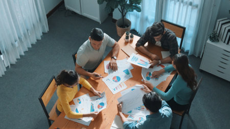 Top down view of start up business team holding paper while discussing about financial idea. Aerial view of smart diverse people brainstorming idea while looking at stock market statistic. Symposium.の写真素材