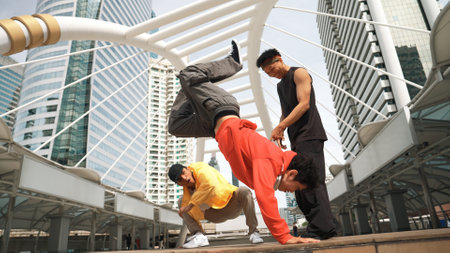 Group of professional happy street dancer cheer up while asian hipster perform b boy dance at urban city surrounded by people with low angle camera. Break dance concept. Outdoor sport 2024. Sprightly.の写真素材