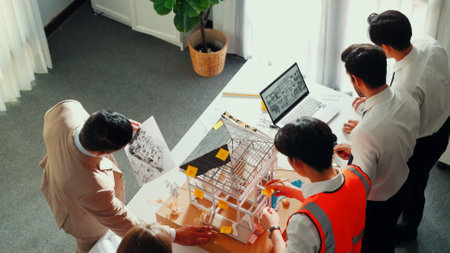 Top view of professional architect engineer team inspect house model while manager holding blueprint and asking about building construction. Group of diverse engineer working together. Alimentation.の写真素材