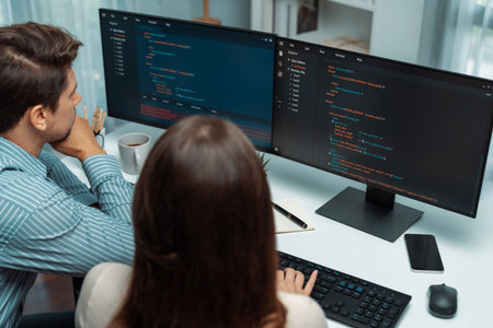 Team skilled developers program coding discussing creative website planning software project on two screen monitors full stack data analyzing design at office with back side view concept. Postulate.の写真素材