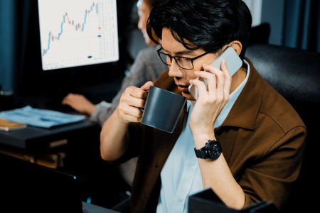 Businessman looking on laptop while calling to broker with calculating margin profit while drinking...