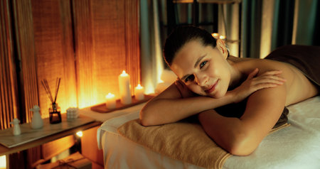 Caucasian woman customer enjoying relaxing anti-stress spa massage and pampering with beauty skin recreation leisure in warm candle lighting ambient salon spa at luxury resort or hotel. Quiescentの写真素材
