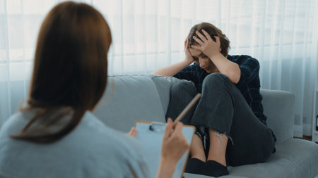 Sad PTSD woman patient in therapy for mental health with psychologist, depression or grief after life failure. Frustrated trauma young woman talking to prim psychologist about emotion in clinicの写真素材