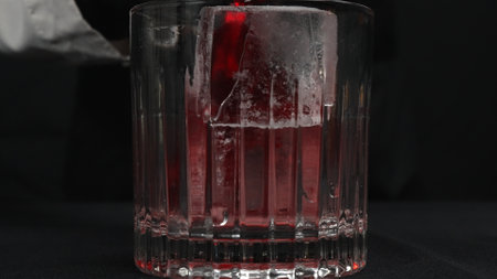 Macrography, observe the skilled hands of a female bartender expertly pouring red syrup in glass...