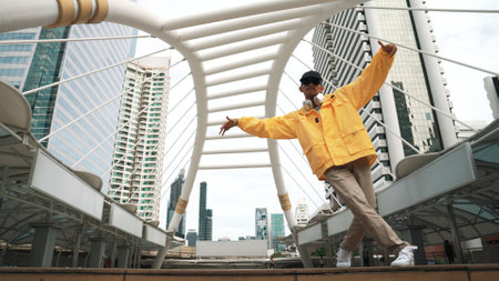 Low angle camera of asian hipster practice break dancing footstep or b-boy performance while wearing headphone. Freestyle dance, break dance, street dance. Lively mood. Outdoor sport 2024. Sprightly.の写真素材