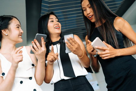 Three women friends having conversation while looking at mobile phone in their hands. Concept of social media, gossip news and online shopping. udsの写真素材