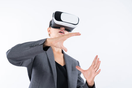 Business woman holding something while wearing VR goggle and standing at white background. Project manager with headset enter visual reality world program by using technology innovation. Contraption.の写真素材