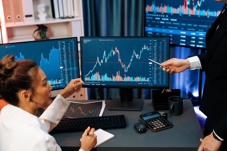 Smiling Asian business traders pointing to dynamic stock exchange data screen profit value online...