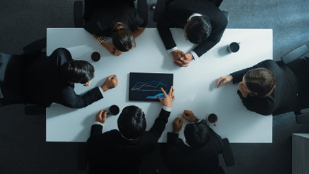 Top down aerial view of professional businessman analyze stock market chart with tablet with investment graph placed at table while investor group pointing at tablet. Creative business. Directorate.の写真素材