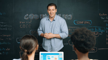 Handsome teacher teaching engineering code to diverse student at blackboard. Happy multicultural highschool children study or learning programing or coding system while using laptop. Edification.の写真素材