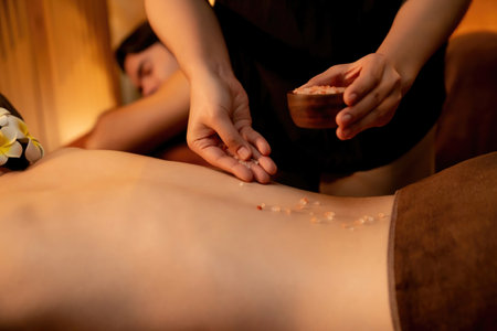 Couple customer having exfoliation treatment in luxury spa salon with warmth candle light ambient. Salt scrub beauty treatment in Health spa body scrub. Quiescentの写真素材