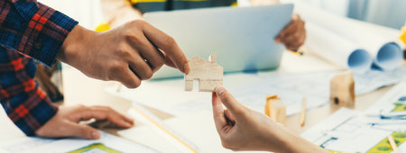 Professional engineer and architect collaborate on eco house project at meeting table with green design blueprint and architectural equipment at modern office. Focus on hand. Close up. Delineation.の写真素材