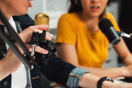 Cropped smiling radio influencer hosts wearing headphones with channel social media online live streaming talking topic on script note and laptop to listeners at morning at studio record. Infobahn.の写真素材
