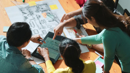 Professional civil engineer handed document while looking at blueprints. Skilled architect team brainstorming idea and planning building design while sitting at meeting table with plans. Symposium.の写真素材