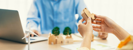 Businesswoman decides to Invest in green business. Skilled architects plan to build a eco house by using renewable energy at table with environmental document scatter around. Close up. Delineation.の写真素材