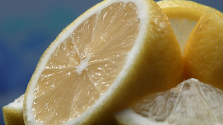 A slice of lemon, bright yellow and vibrantly citric, lies exposed. The yellow flesh, with refreshing juice, reveals its segmented interior. The essence of citrus vibrancy. Slow motion. Comestible.の写真素材