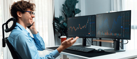 Successful smiling young investor in stock trader calling on smartphone to business partner earning...