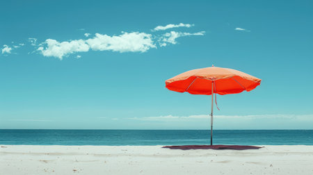 A vibrant beach umbrella provides shade on the sandy shore overlooking the sparkling ocean, with people enjoying the coastal natural landscape under a clear sky AIG50の素材