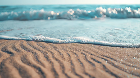 A close up of a sandy beach with waves crashing onto the shore, showcasing the beauty of natures water and wind waves in a natural landscape AIG50の素材