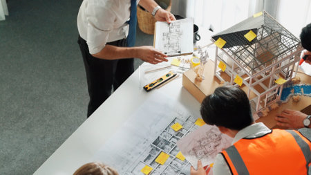 Top view of professional architect engineer team inspect house model while manager holding blueprint and asking about building construction. Group of diverse engineer working together. Alimentation.の写真素材