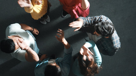 Top down aerial view of smart business people putting hands together to celebrate successful project while sitting chair circle. Aerial view of skilled marketing team making stack of hands. Symposium.の写真素材