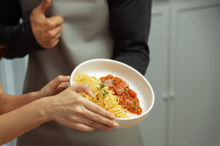 Close up of hand couple chef influencers completely cooked spaghetti with meat topped with tomato...