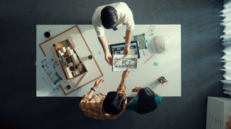 Top down view of civil architect looking at project plan while present to investor at meeting table. Aerial view of skilled designer explain about construction to business people listen. Alimentation.の写真素材