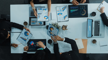 Top down aerial view of business people discussing about financial strategy on table with document...