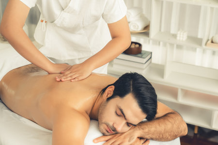 Caucasian man customer enjoying relaxing anti-stress spa massage and pampering with beauty skin recreation leisure in day light ambient salon spa at luxury resort or hotel. Quiescentの写真素材