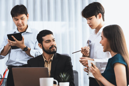 Professional Asian employee work together as team in corporate office, discussing business plans and data to achieve success on desk with laptop. Modern office worker teamwork concept. Concordの写真素材