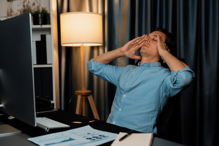 Thinking of stressful financial analyst researching on business paragraph on pc screen with dynamic database marketing analysis planning monthly report at modern home office at night time. Pecuniary.の写真素材