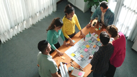 Top view of civil engineer team writing at blueprint at meeting table with color palettes. Group of smart diverse people planning and taking a note while manager looking at project plans. Symposium.の写真素材