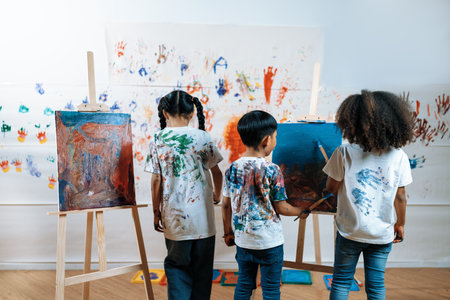 Students painting on canvas show artist skill in drawing class. Kid paint canvas all around use paintbrushes with blue and red as main color. Wall put paper printed with hand of children. Erudition.の写真素材