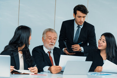 Senior caucasian manager working in office with assistance of young Asian business people and translator in meeting. Corporate international business and secretary language translation concept. udsの写真素材