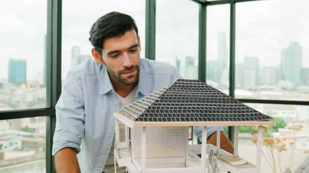 Professional architect engineer check, inspect, look architectural model at modern office with skyscraper, cityscape view. Skilled project manager or businessman check house construction. Traceryの写真素材