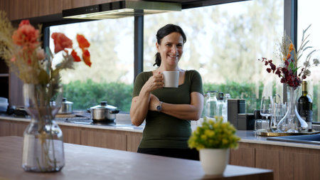 Happy old grandmother confidently standing pose while look at camera for good event or anniversary in kitchen. Cheerful senior enjoy retirement life with beautiful kitchenware and house. Divergence.の写真素材