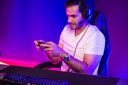 Smart gaming streamer talking with team member players with joystick to control game, mic for...