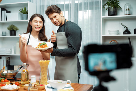 Couple chef influencers completely cooked spaghetti with meat topped with tomato sauce special dish recording on camera with live chanel. Concept of serving healthy food at modern home. Postulate.の写真素材