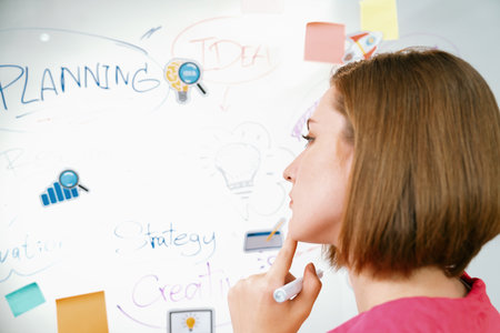 Portrait of young beautiful caucasian businesswoman thinking creative marketing strategy idea in front of whiteboard with mind map and colorful sticky notes. Arm chin. Closeup. Immaculate.の写真素材
