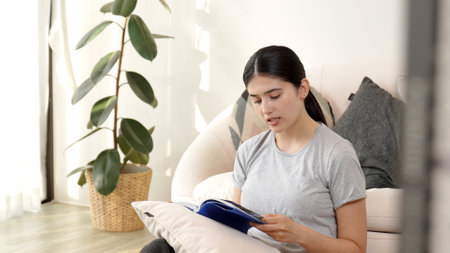Middle age woman sitting on sofa read textbook increase knowledge about social and technology for...