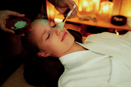 Serene ambiance of spa salon, woman customer indulges in rejuvenating with luxurious face cream massage with warm lighting candle. Facial skin treatment and beauty care concept. Quiescentの写真素材