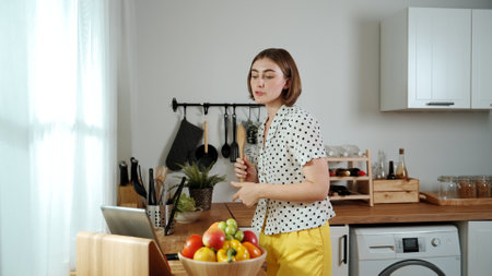 Caucasian mother prepare food for making salad while looking at food recipe in laptop at modern...