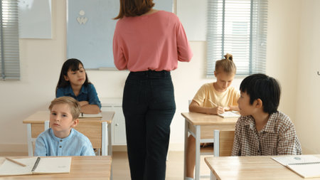 Caucasian teacher walking around classroom while explain classwork. Attraction instructor talking and explain lesson while diverse student listening ans working or taking a note. Education. Pedagogy.の写真素材